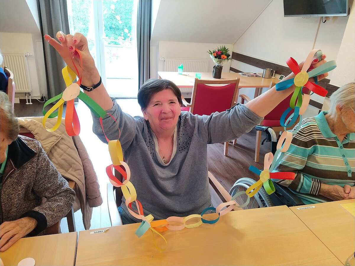 Bewohnerin präsentiert ihre selbstgemachte Blumenkette.