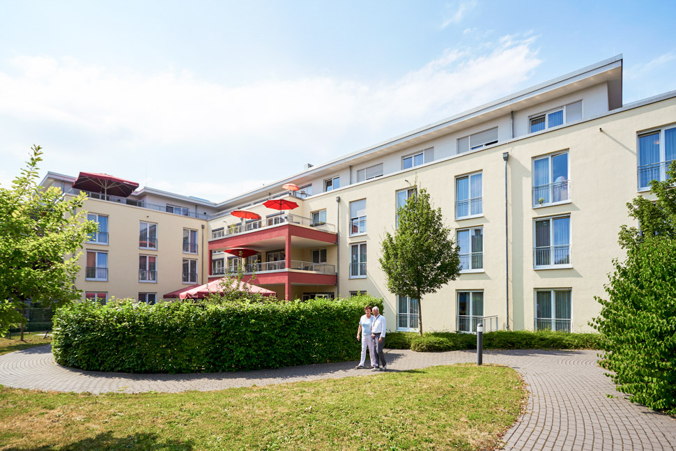 Pflegekraft und Bewohner gehen im Park der Alloheim Senioren-Residenz Löwenquell in Bad Rodach spazieren